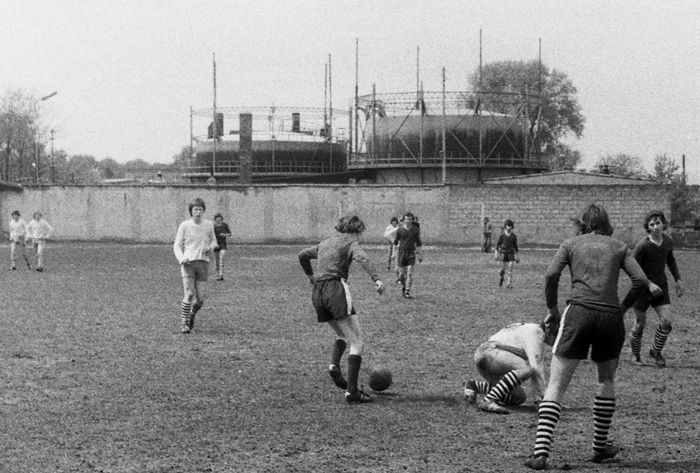 Mecz na boisku PIAST, Ostrzeszów, ul. Sportowa, w tle zbiorniki gazowni, 1975 r., fot. M. Dytfeld